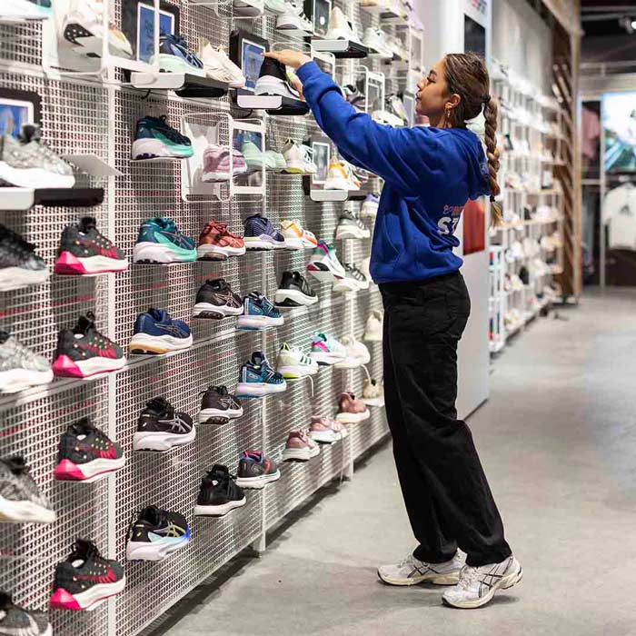 Employee from Intersport in Frederiksberg Center, placing shoes on the shelf.